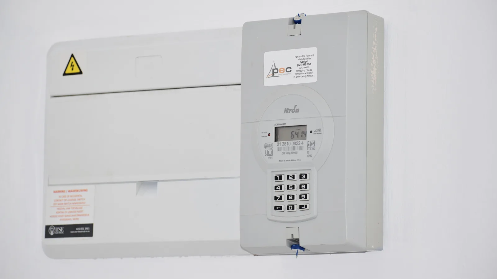 Closed wall-mounted electrical meter and fuse box on a white wall