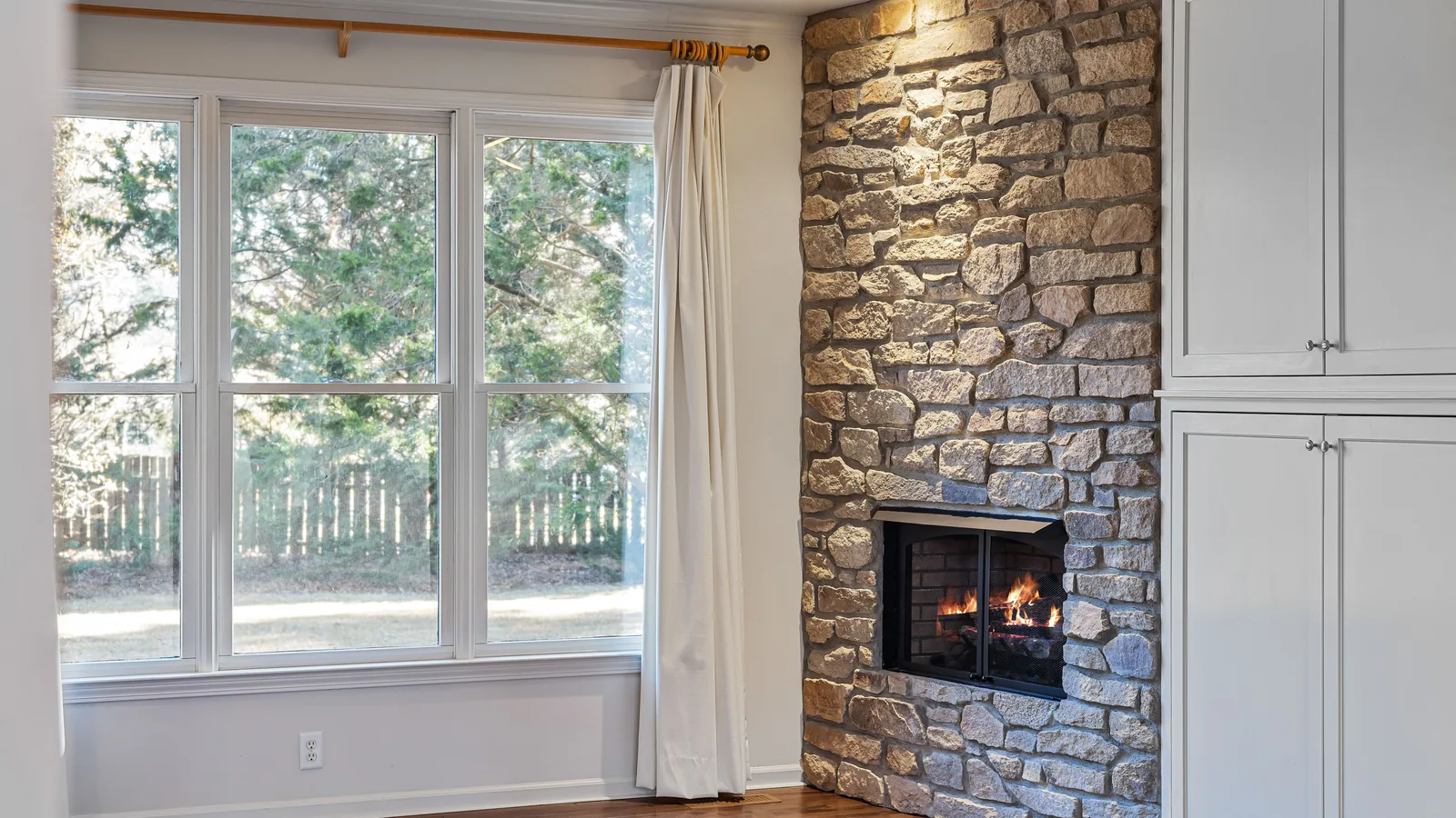 Curtain rod mounted above a wide living room window with floor-length panels