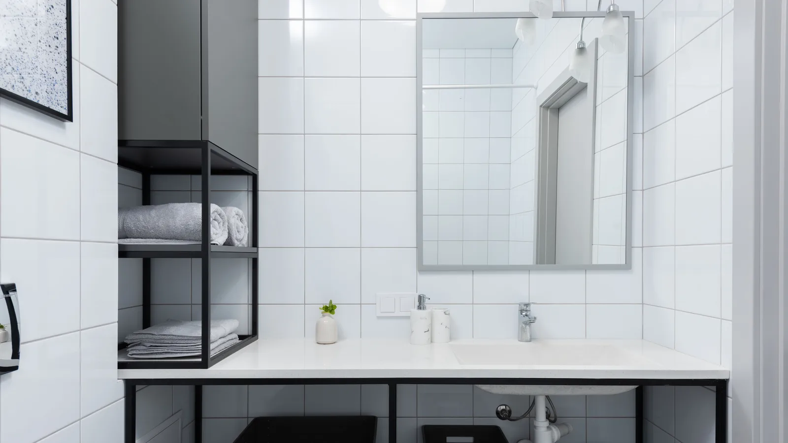 Open bathroom vanity with exposed sink plumbing and two black storage bins